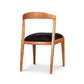 Montgomery Chair by Vermont Woods Studios with natural cherry frame, curved back, and black seat, highlighted from the back to showcase design details.