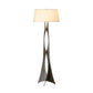 A Hubbardton Forge Moreau Floor Lamp with a metal base and a beige shade.