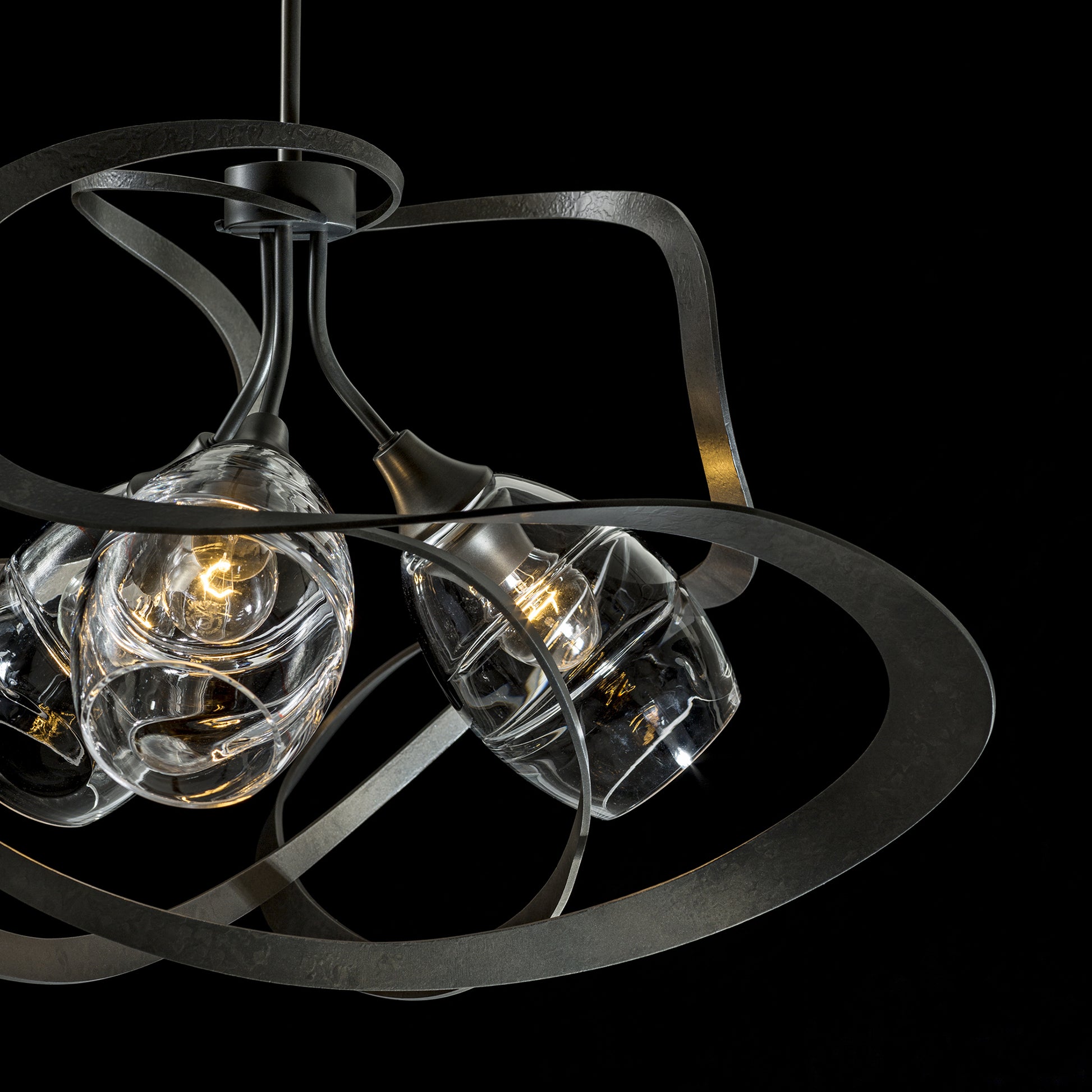A handcrafted Hubbardton Forge Nest Pendant with three glass shades and a metal frame.