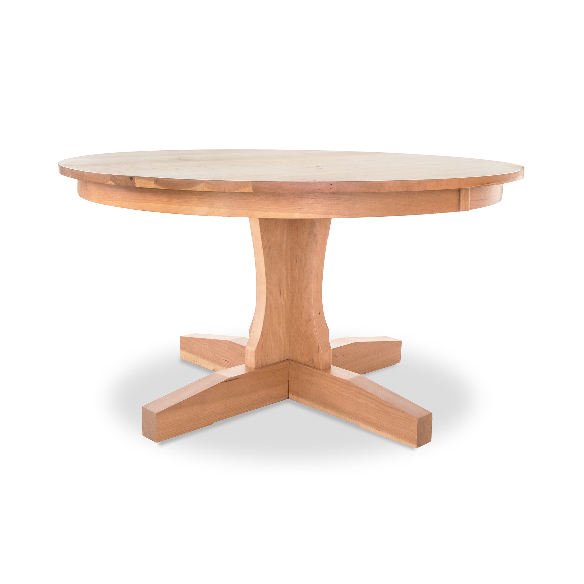 A Lyndon Furniture New Traditions Round Pedestal Table with four legs and a natural finish on a white background.