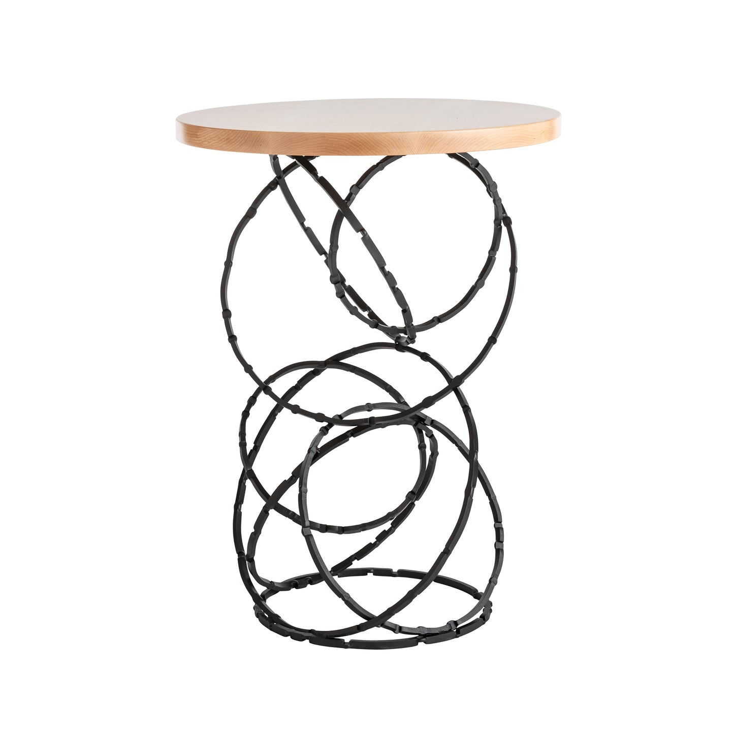 The Olympus Wood Top Accent Table by Hubbardton Forge features a small, round top made of light Vermont maple wood and a base of interlocking black steel loops arranged in a circular pattern. This design combines modern style with artistic elements for a sculptural appearance.