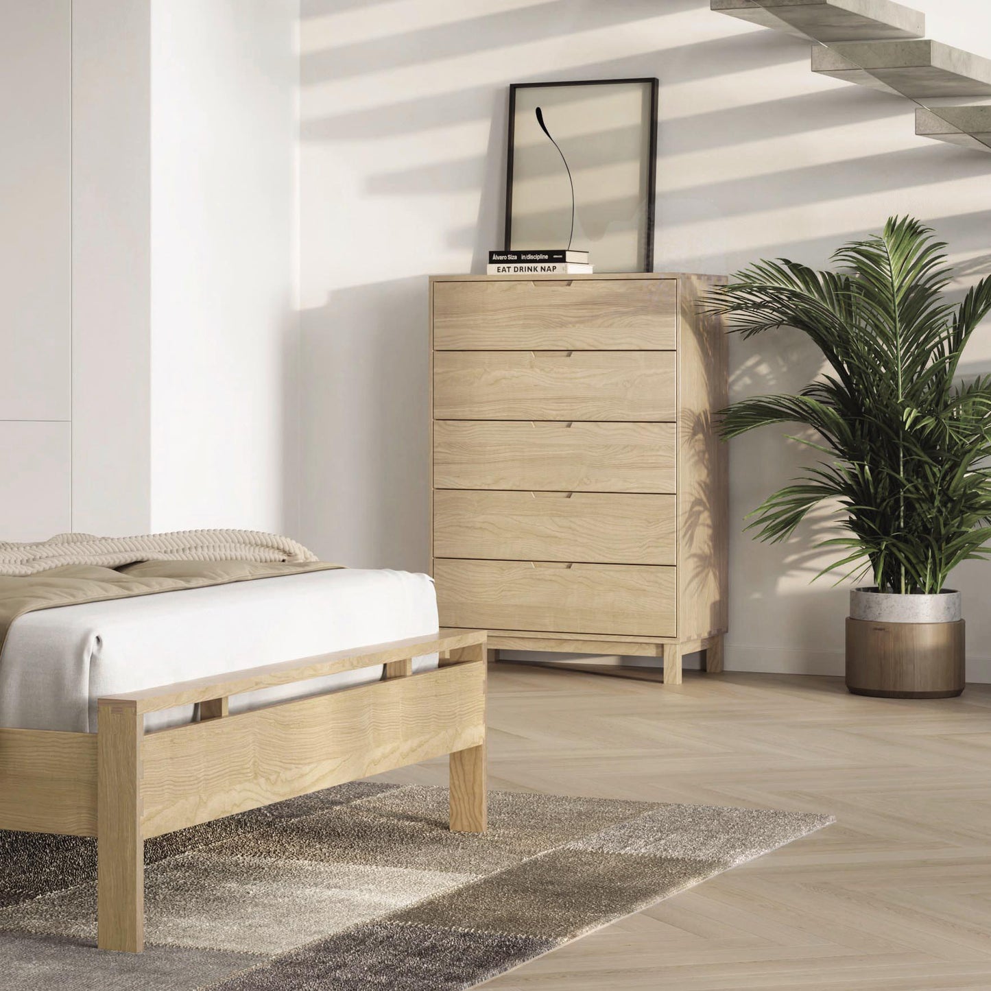 A modern bedroom featuring the Copeland Furniture Oslo 5-Drawer Wide Chest, with a solid oak hardwood bed frame and matching Oslo Bedroom Furniture Collection, a plant in a metallic pot, a small mirror on the dresser.