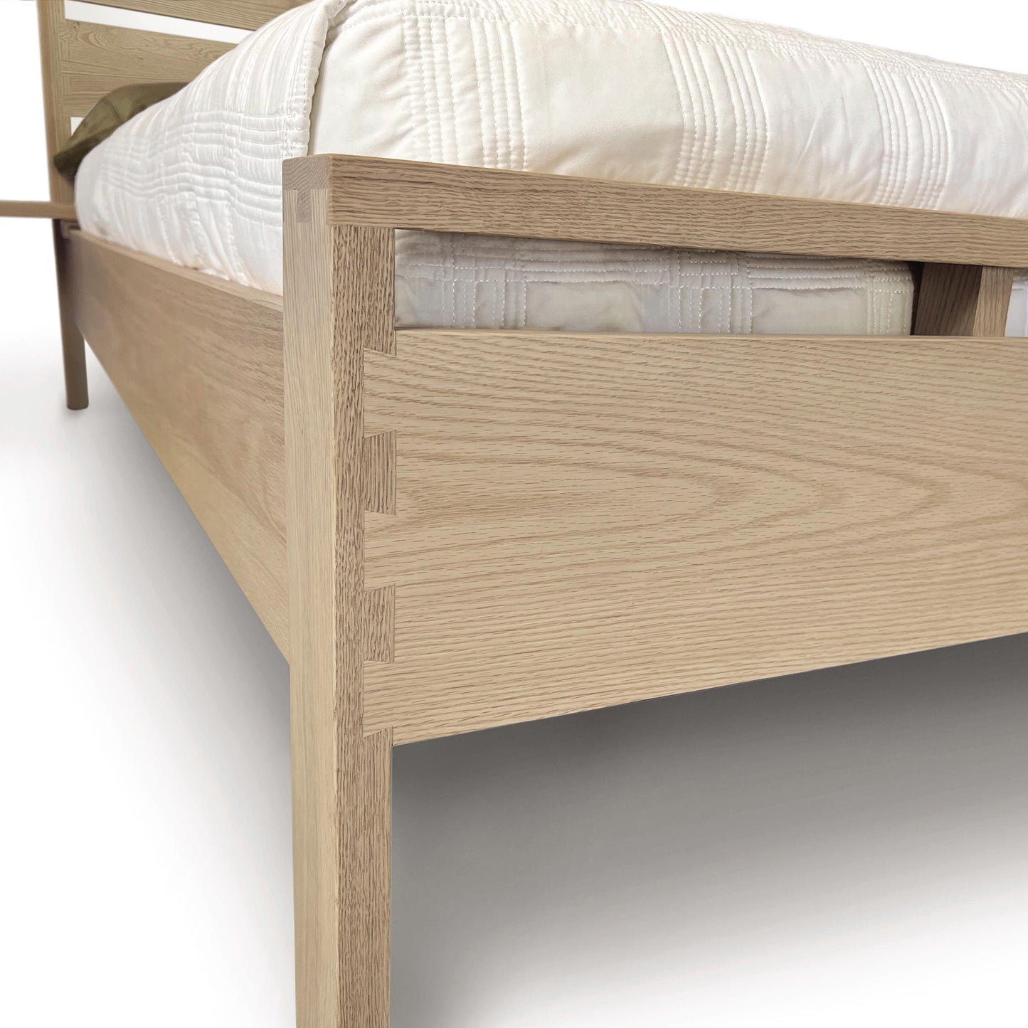 Part of a minimalist Copeland Furniture Oslo Platform Bed frame with a clear focus on the solid oak hardwood headboard and corner joint, showcasing the wood grain and construction details.
