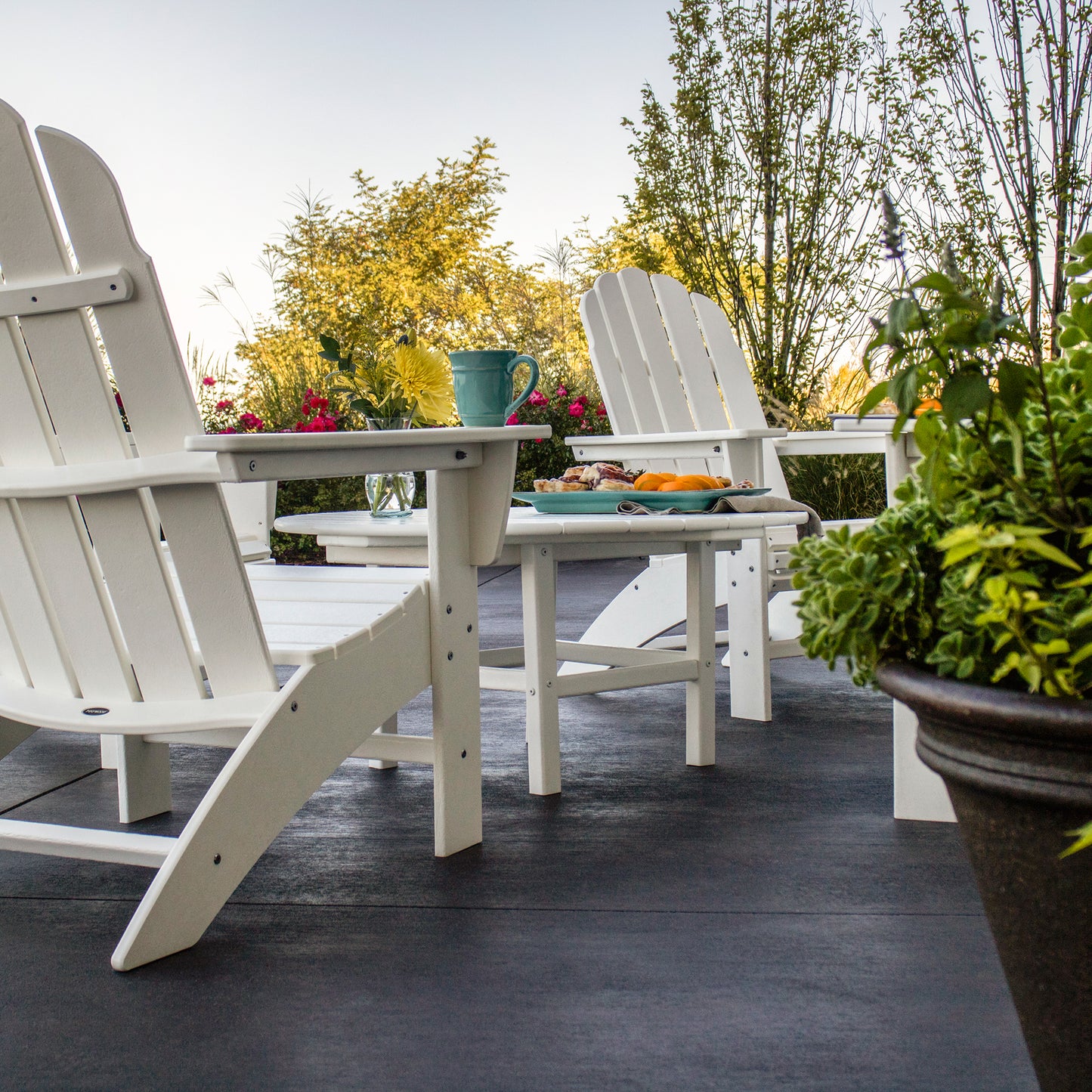 White POLYWOOD Adirondack chairs and a matching 38" Conversation Table arranged together, showcasing premium American-made outdoor furniture.