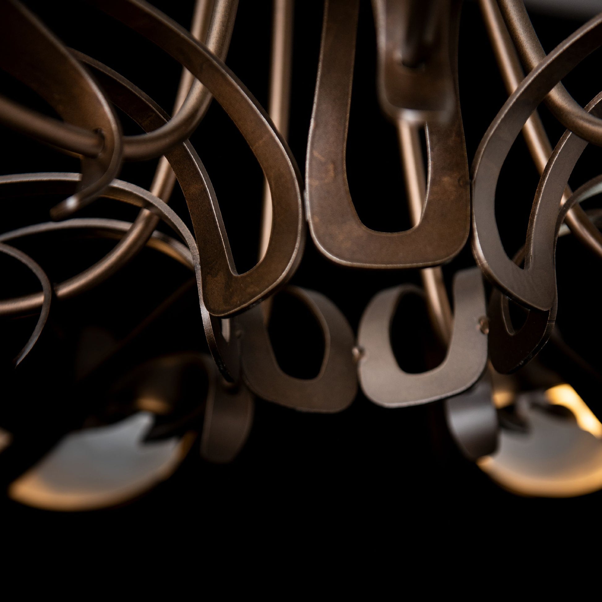 Curved, hand-forged steel arms and bronze detailing on the Parasol 7-Light Chandelier by Hubbardton Forge, showcasing its elegant craftsmanship.