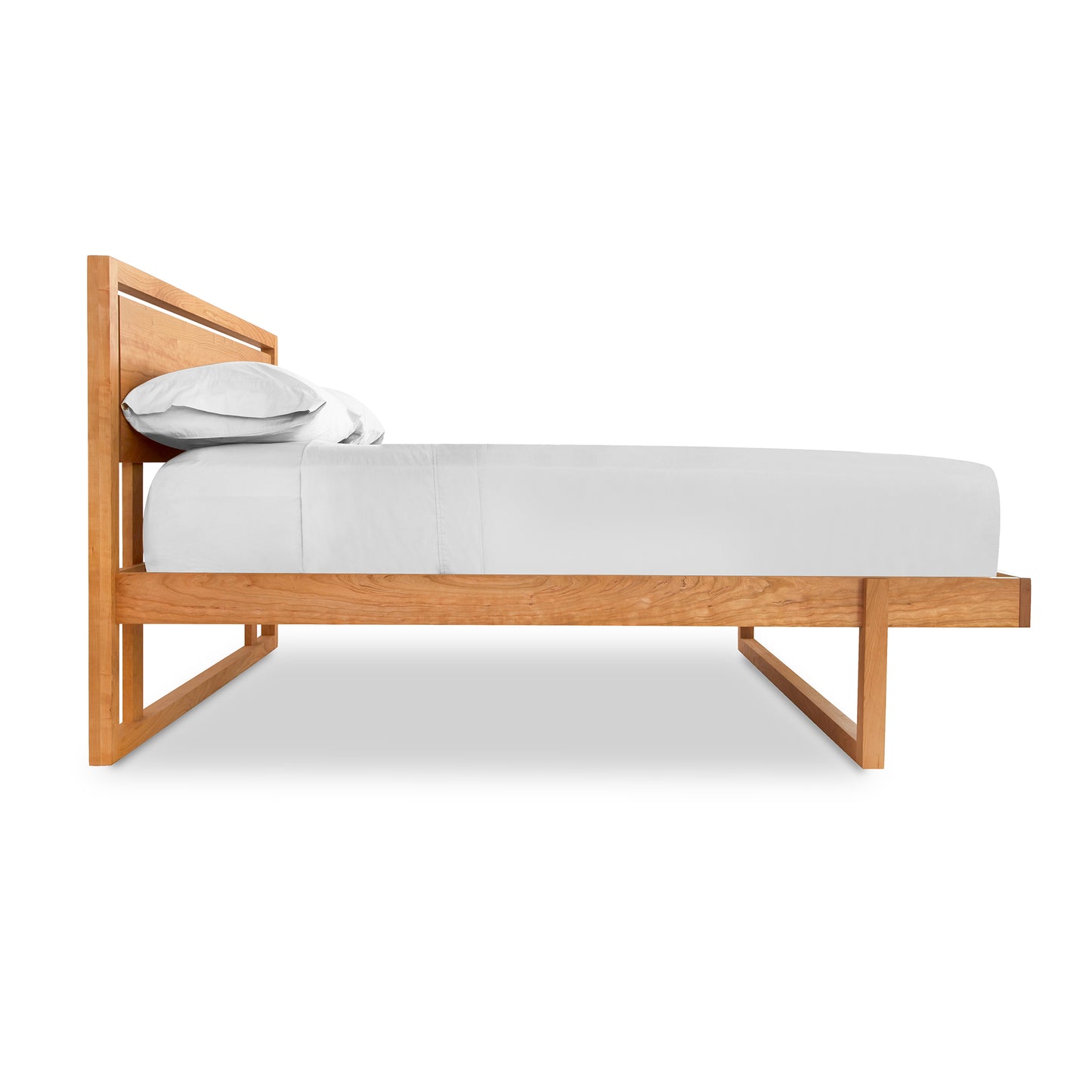 A Vermont Furniture Designs Pendant Bed with a cherry wood frame and white sheets.