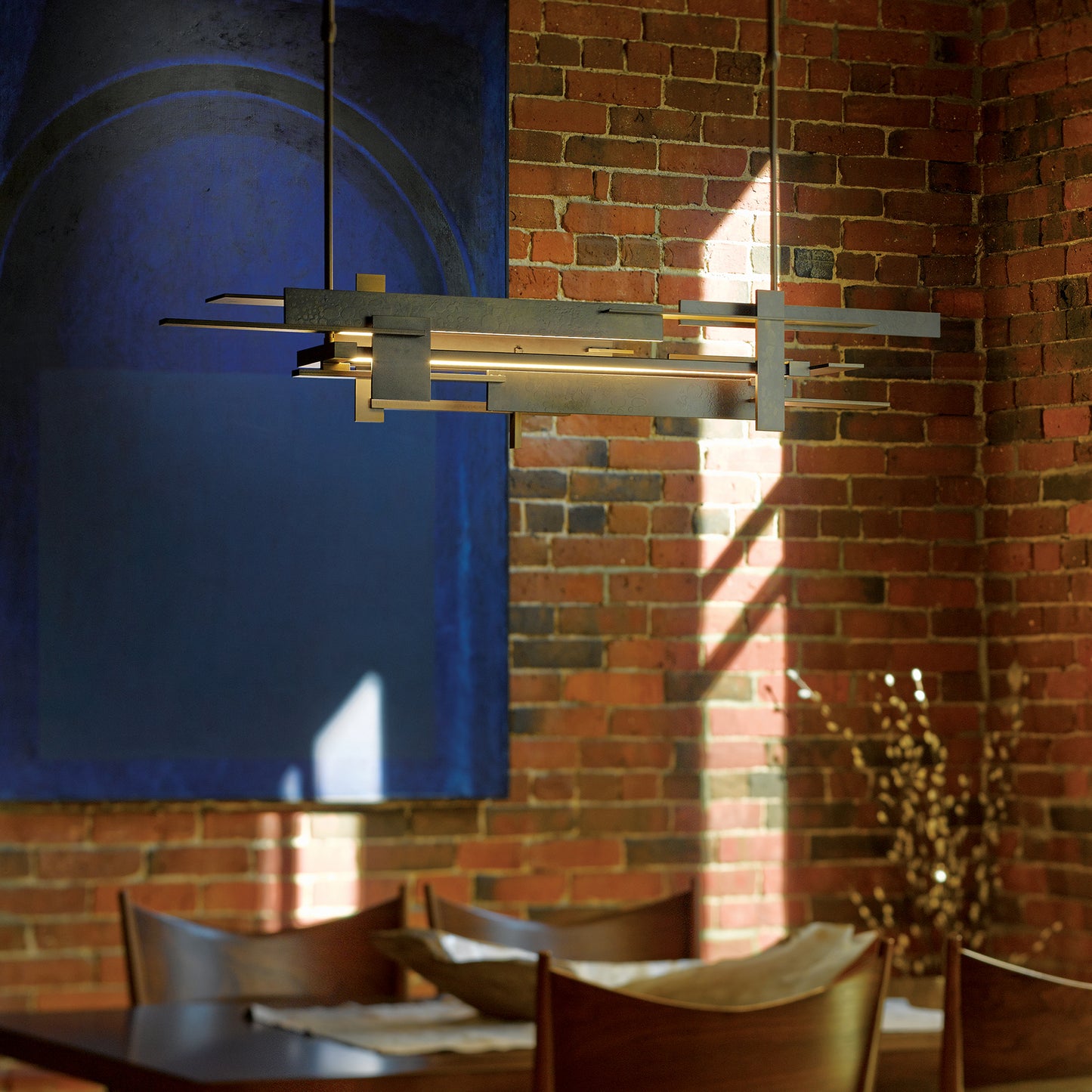 A dining room with a Frank Lloyd Wright inspired table and chairs, accented by the elegant glow of a Planar LED Pendant from Hubbardton Forge.