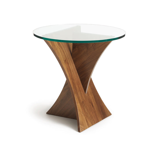 A modern Planes Round Glass Top End Table with a natural walnut base featuring an x-shaped design by Copeland Furniture.