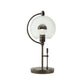 A Hubbardton Forge Pluto Table Lamp with a glass globe on top.