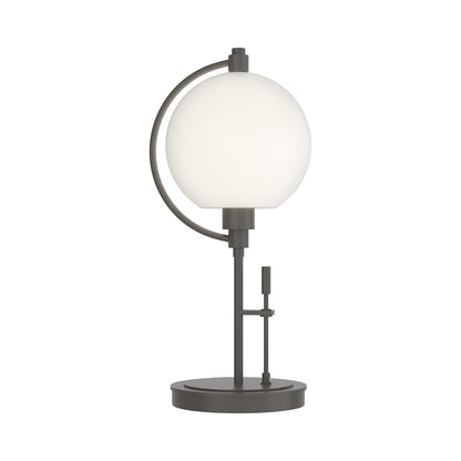 Pluto Table Lamp by Hubbardton Forge featuring a round white glass shade, black metal base, and modern circular support design.