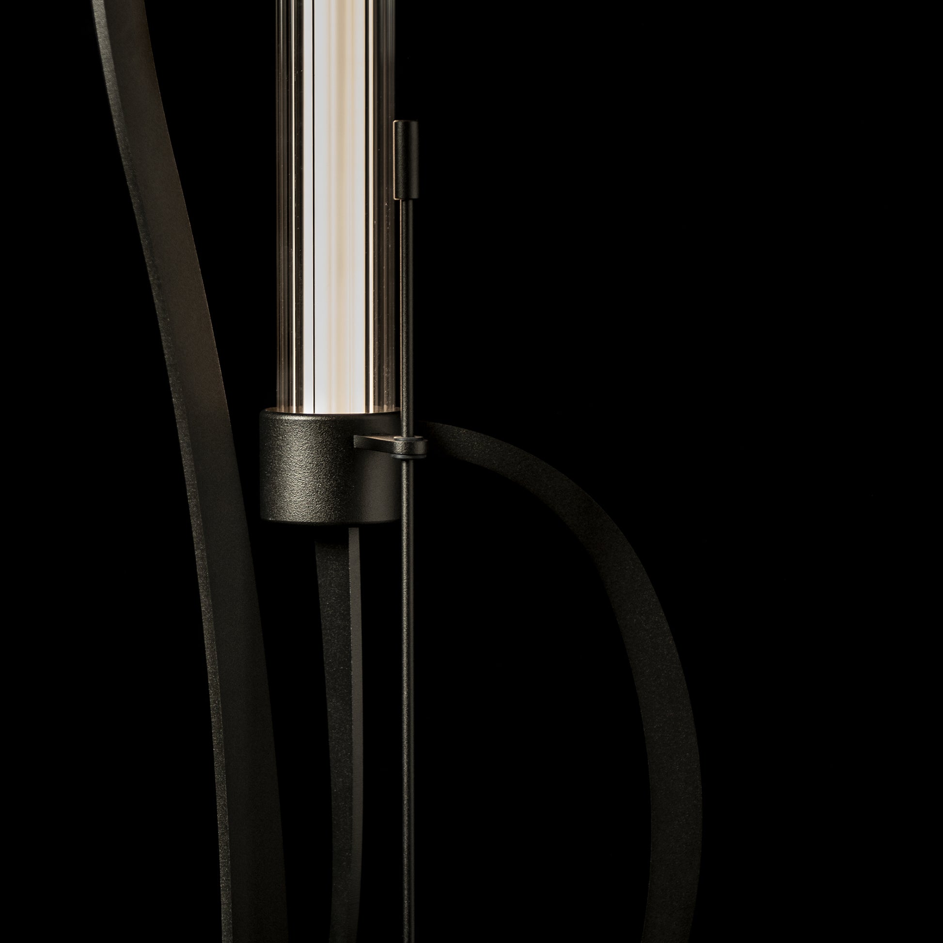 Hubbardton Forge Pulse Floor Lamp featuring a cylindrical glass shade and a sleek black hand-forged steel frame.