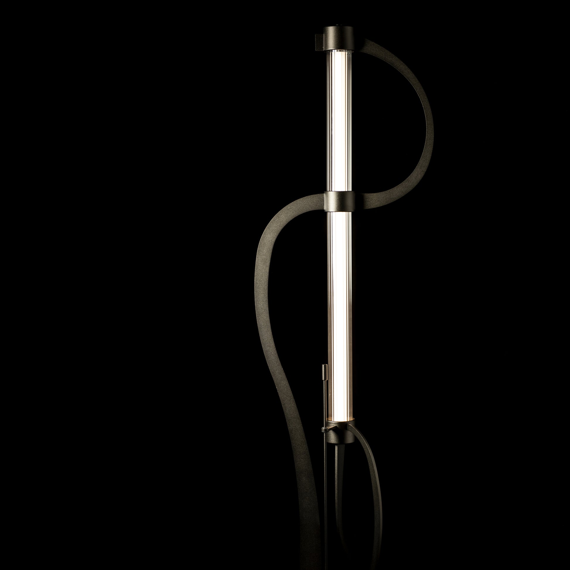 Hubbardton Forge Pulse Floor Lamp with sleek design featuring an LED tube inside a vertical cylindrical light, supported by two gracefully curved black supports.