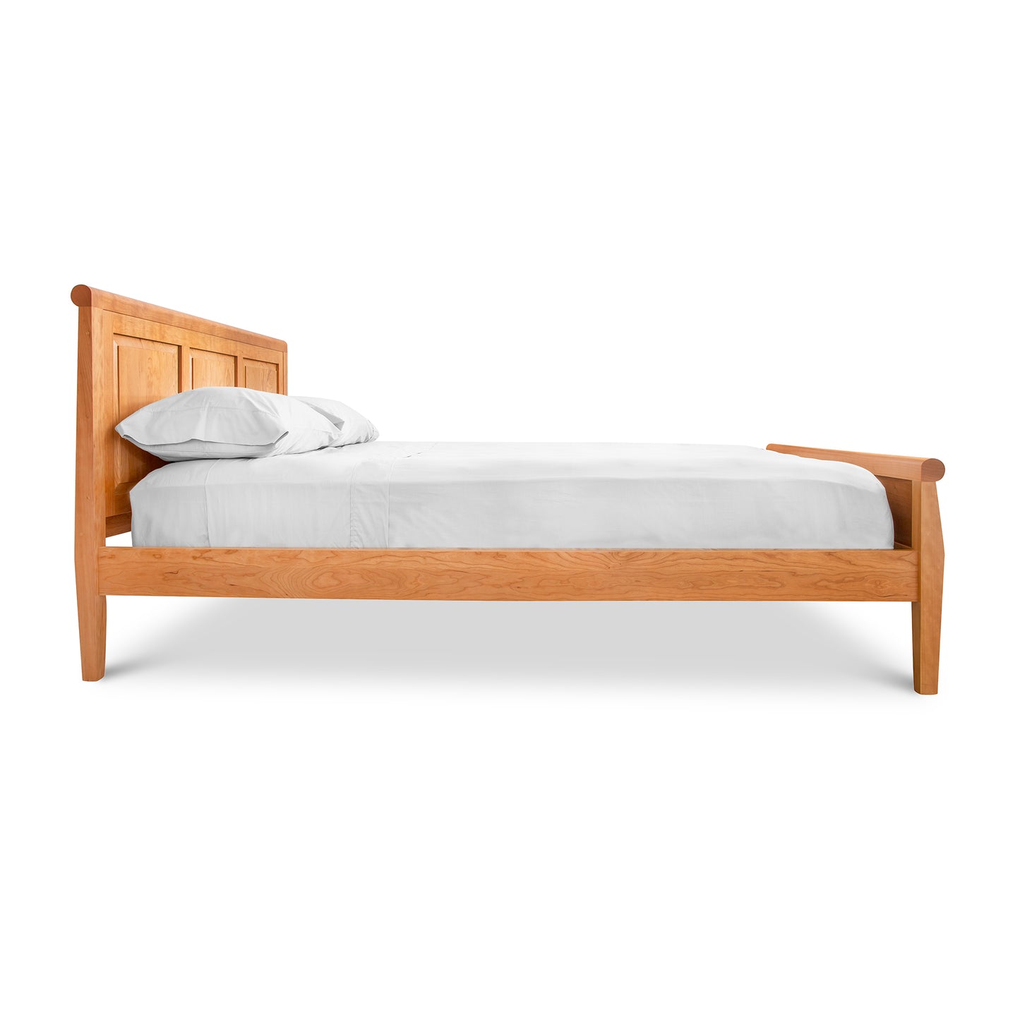 Raised Panel Carriage High Footboard Bed by Lyndon Furniture featuring a sleek design with a white mattress and two pillows, side view.