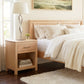 The Rockingham 1-Drawer Nightstand by Vermont Woods Studios, featuring American made craftsmanship, displayed beside a bed in a modern setting.