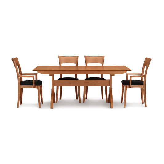 A Sarah Shaker Trestle Extension Table from Copeland Furniture with four chairs. This solid wood fine dining furniture features a self-storing leaf for added convenience.