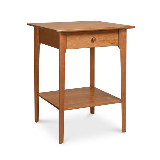 A small wooden nightstand with a Shaker design, called the "Sarah 1-Drawer Open Shelf Nightstand" by Copeland Furniture.