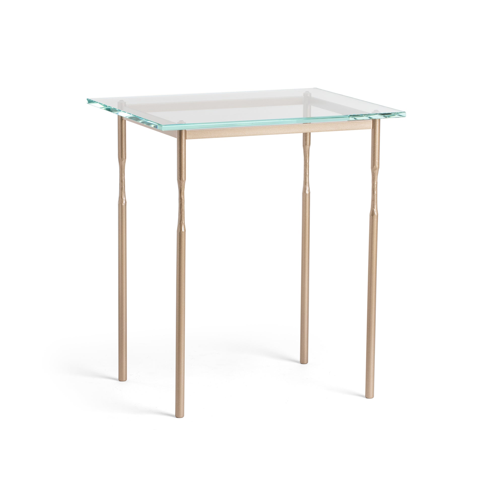 The Hubbardton Forge Senza Side Table is a modern addition to any home. With its fine tailoring and elegant design, this end table features a glass top and gold legs, adding a touch of sophistication.