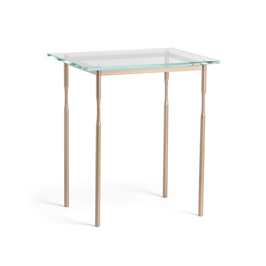 The Hubbardton Forge Senza Side Table is a modern addition to any home. With its fine tailoring and elegant design, this end table features a glass top and gold legs, adding a touch of sophistication.