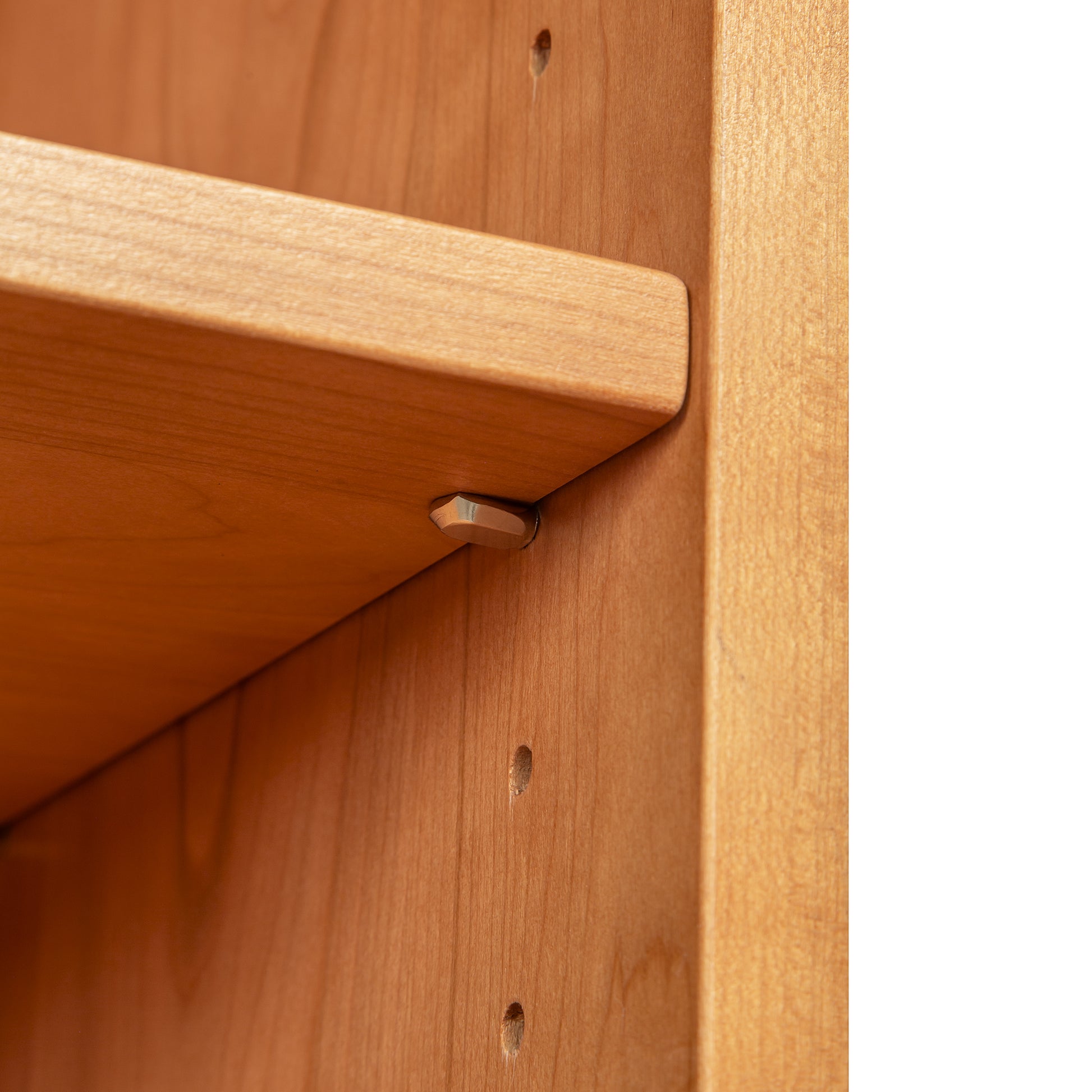 Detail of a Lyndon Furniture Shaker Bookcase shelf with metal pegs and adjustable holes, highlighting customizable American craftsmanship.