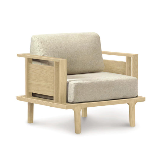 A modern Sierra Oak Upholstered Chair by Copeland Furniture with custom upholstery and light beige cushions on a white background.