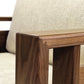 A close-up view of a wooden table corner with a Copeland Furniture Sierra Walnut Upholstered Chair in the background.