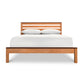 A natural eco-friendly Vermont Furniture Designs Skyline Panel Bed, handmade-to-order, with white sheets.