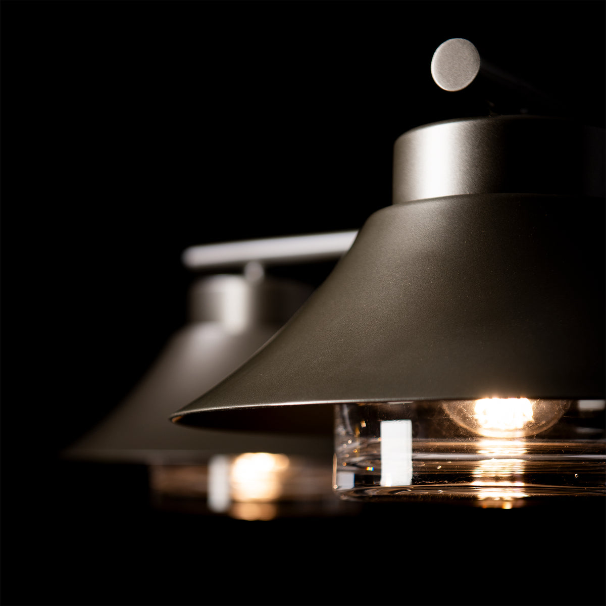 Two hand-forged steel Stowe Outdoor 4-Light Pendant fixtures featuring wide shades and glowing glass bulbs.