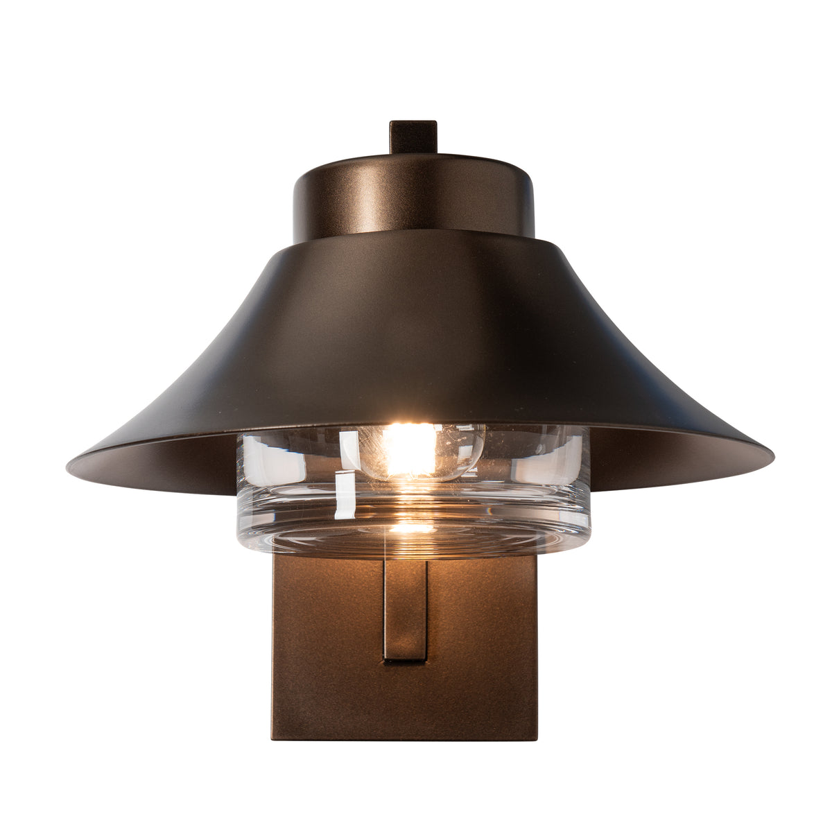 Stowe Outdoor Sconce in dark bronze, featuring a hand-forged steel frame, wide metal shade, and a clear ribbed glass cylinder with a lit bulb.