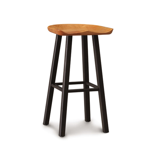 A Modern Farmhouse Tractor Bar Stool with a natural finish seat and black legs stands isolated on a white background. (Copeland Furniture)