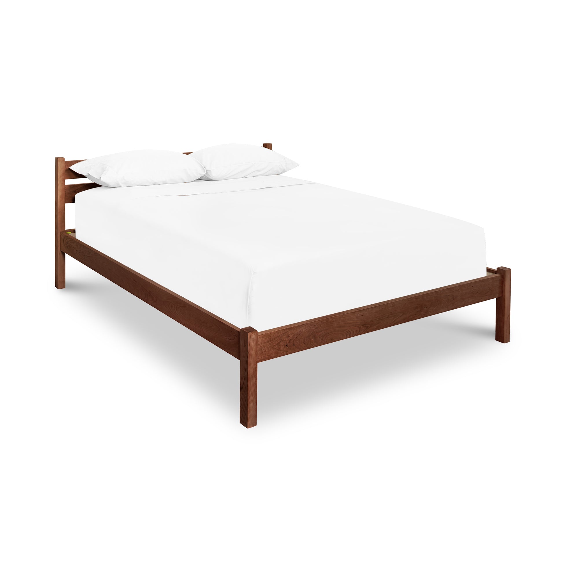 Vergennes Platform Bed featuring a handcrafted wooden frame made from sustainable hardwoods, complemented by a white mattress and two matching white pillows.