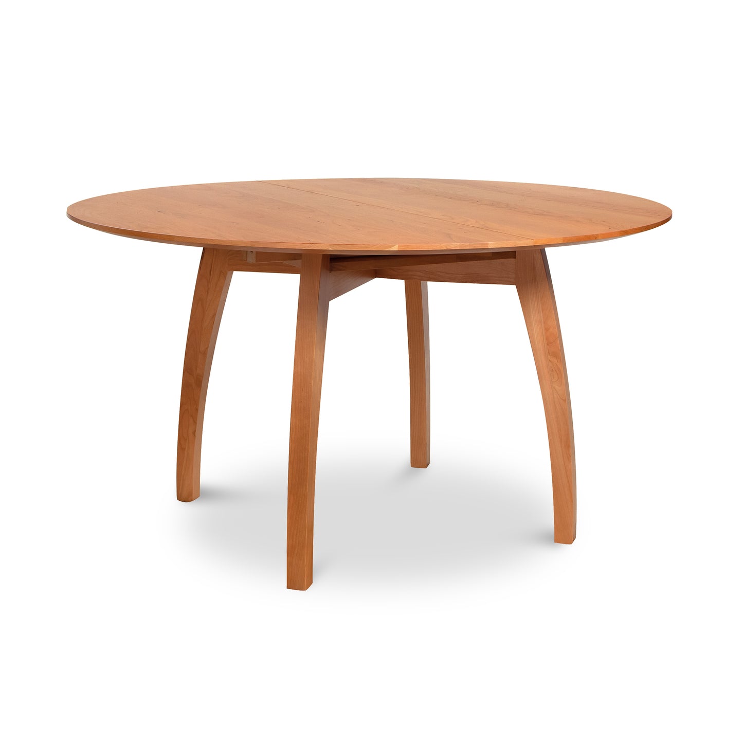 An elegant handcrafted Vermont Modern Round Pedestal Extension Table by Lyndon Furniture, featuring a natural wood finish and contemporary design with a smooth surface and four slightly curved legs. This solid wood extension table epitomizes high-quality American craftsmanship. The image has a white background, emphasizing the fine details of this cherry wood furniture piece.