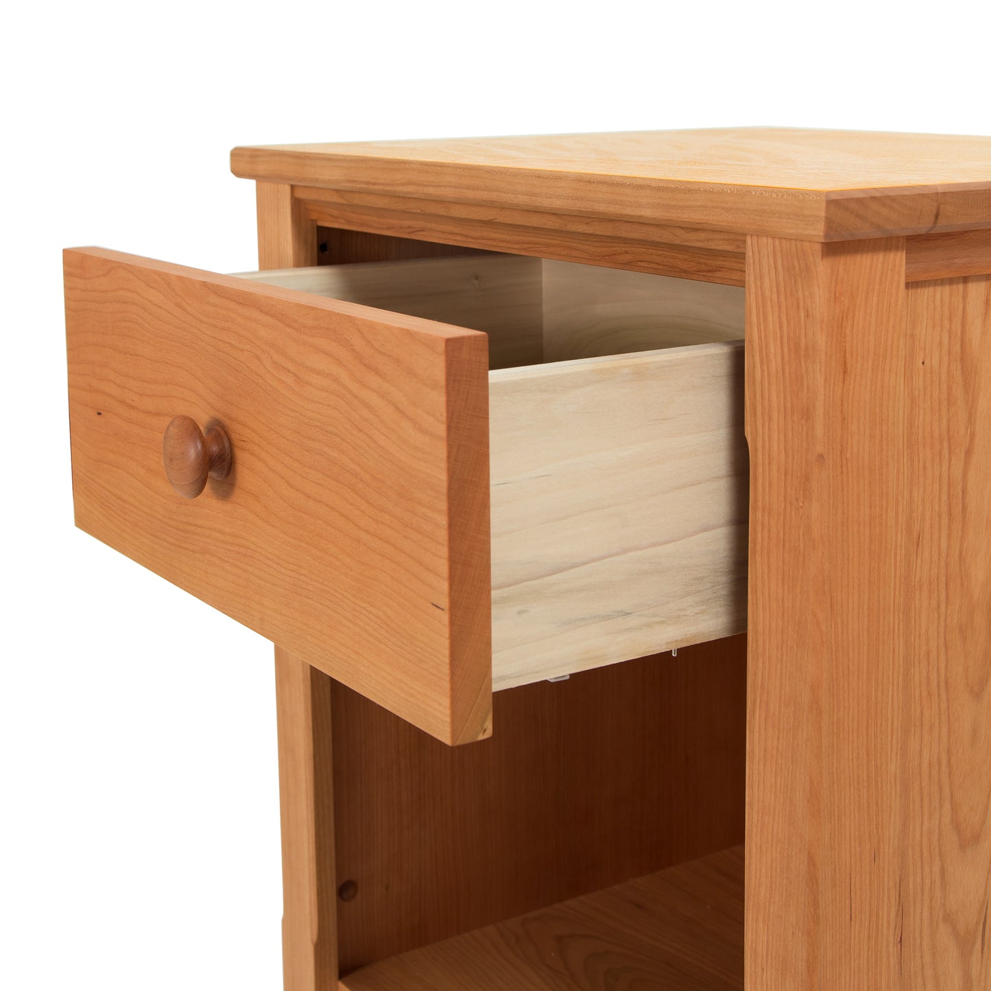 A close-up of an open drawer in a Maple Corner Woodworks Vermont Shaker 1-Drawer Enclosed Shelf Nightstand, showing the natural cherry wood grain and simple knob handle, against a white background.