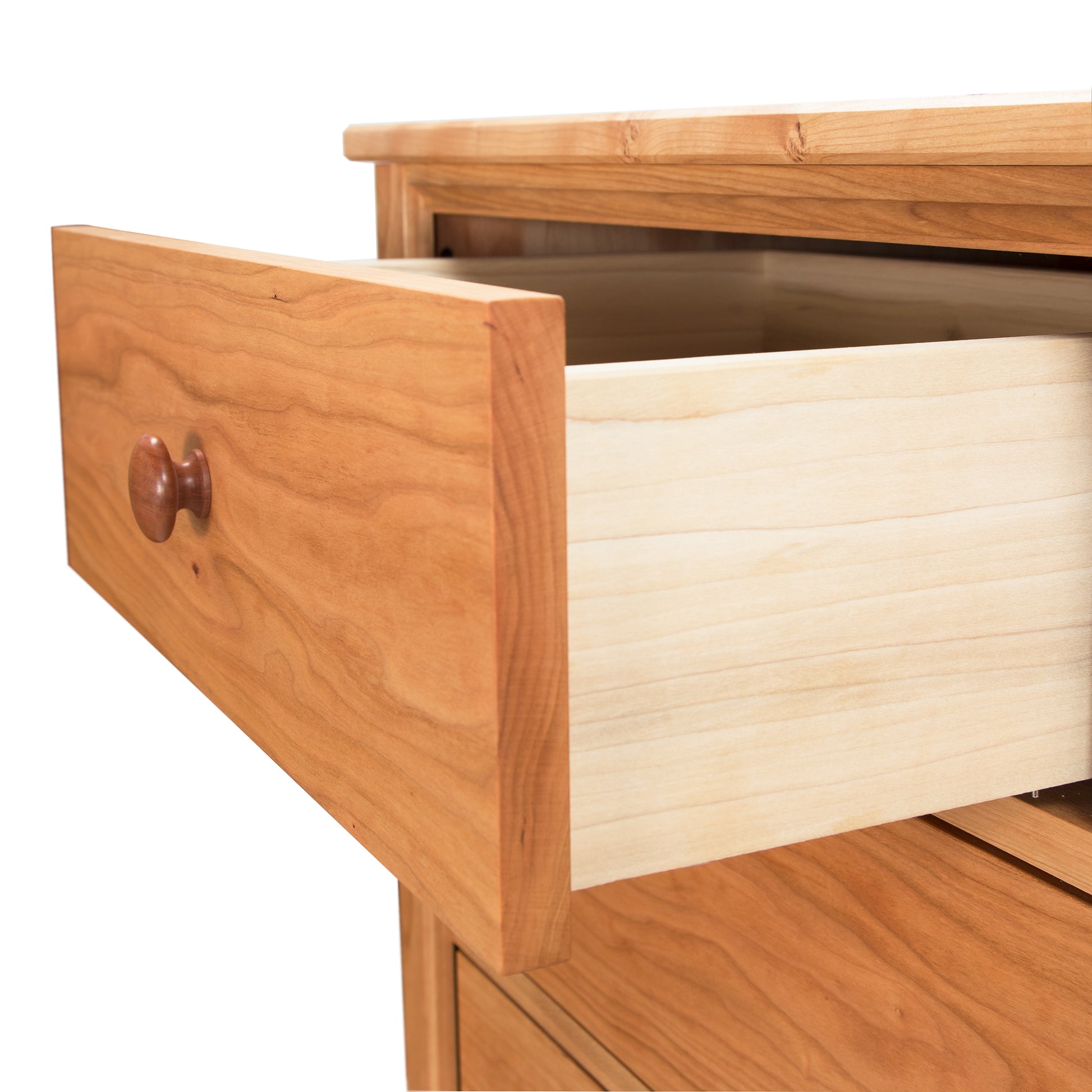 A Vermont Shaker 7-Drawer Dresser by Maple Corner Woodworks with an open drawer, showing the light-colored interior and wooden knob, set against a white background.