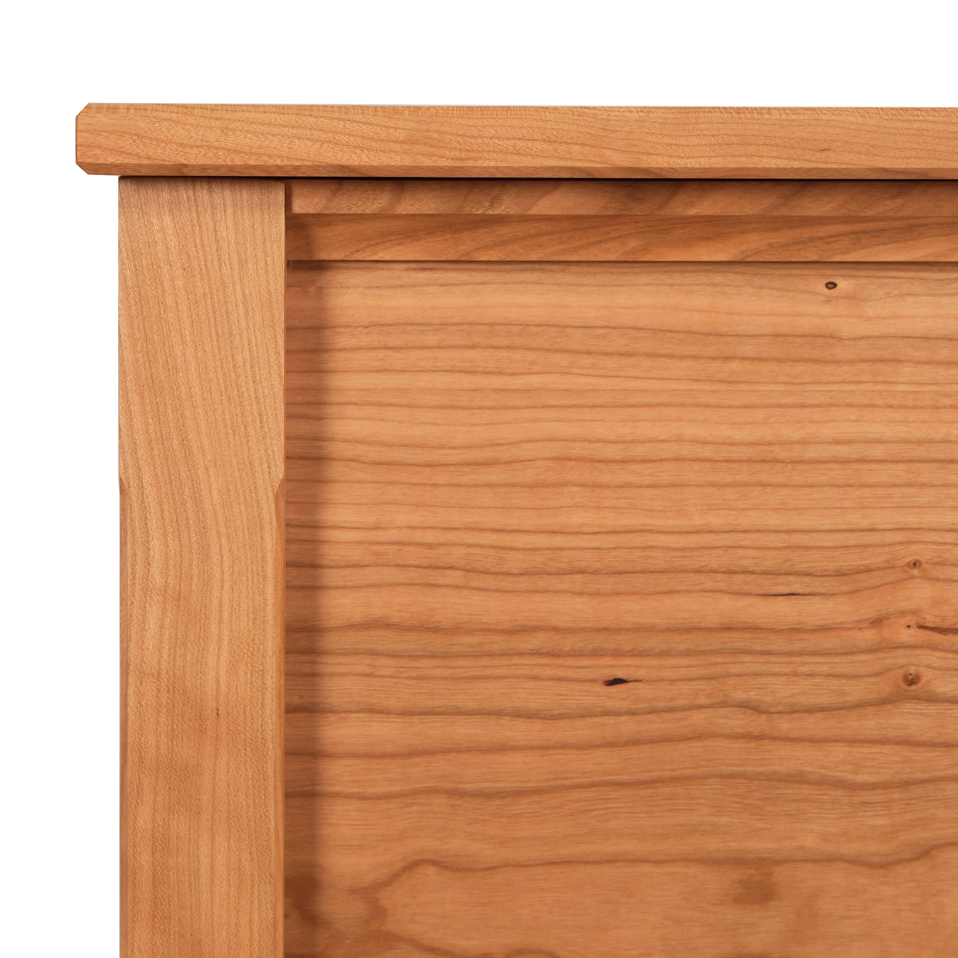 Close-up view of a wooden Maple Corner Woodworks Vermont Shaker Blanket Chest corner showing the detailed wood grain and joinery, with a lighter wood used for the front panel and a slightly darker tone for the frame.