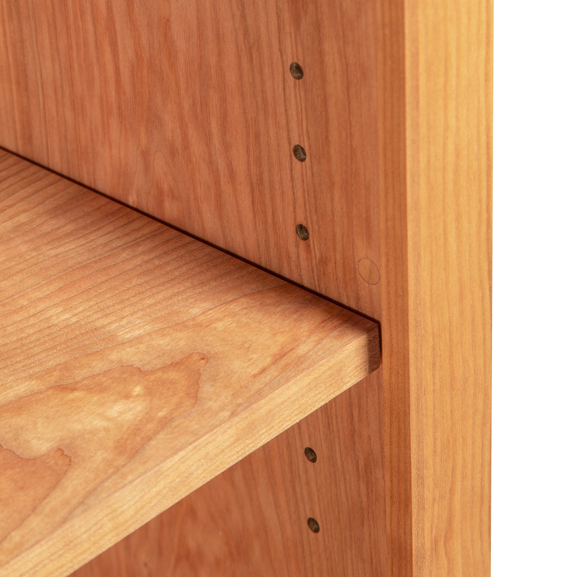 Vermont Shaker Bookcase by Maple Corner Woodworks highlighting its adjustable peg holes, smooth surface, and rich grain pattern of premium hardwood.