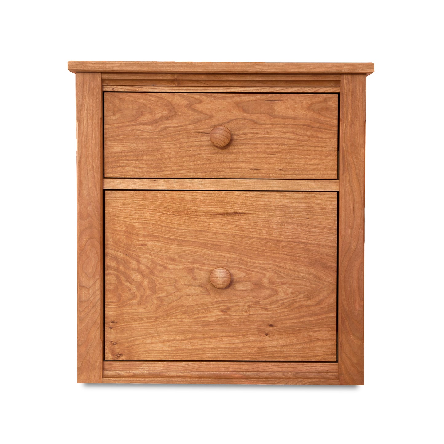 The Vermont Shaker File Cabinet by Maple Corner Woodworks is a wooden bedside table with two drawers adorned with round knobs. Featuring a natural wood finish and a rectangular shape with a flat top, it reflects the meticulous craftsmanship of Vermont artisans.