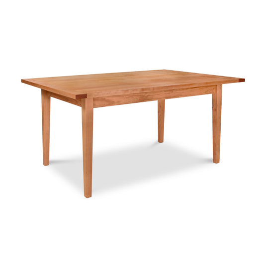 A handcrafted wooden rectangular table with a smooth surface and tapered legs, the Vermont Shaker Harvest Extension Dining Table by Maple Corner Woodworks is made of light-colored, sustainably harvested wood and is showcased on a white background.