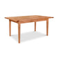 The Vermont Shaker Harvest Extension Dining Table by Maple Corner Woodworks is a handcrafted piece featuring a wooden rectangular design with four sturdy legs set against a pristine white background. Made from sustainably harvested woods, it offers a smooth surface and boasts a natural wood finish.