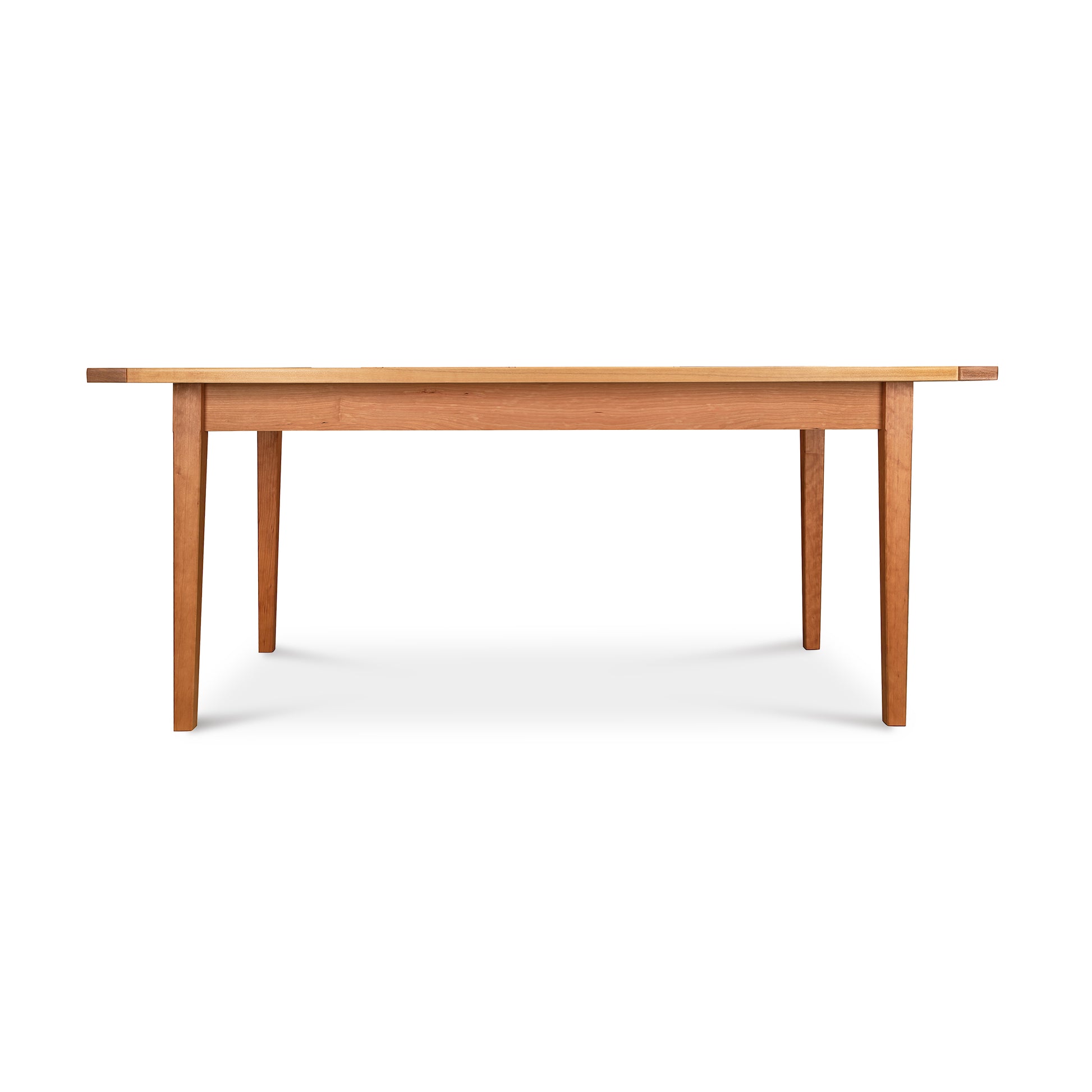A simple Vermont Shaker Solid Top Harvest Table with a smooth top and four sturdy legs, isolated on a white background by Maple Corner Woodworks.