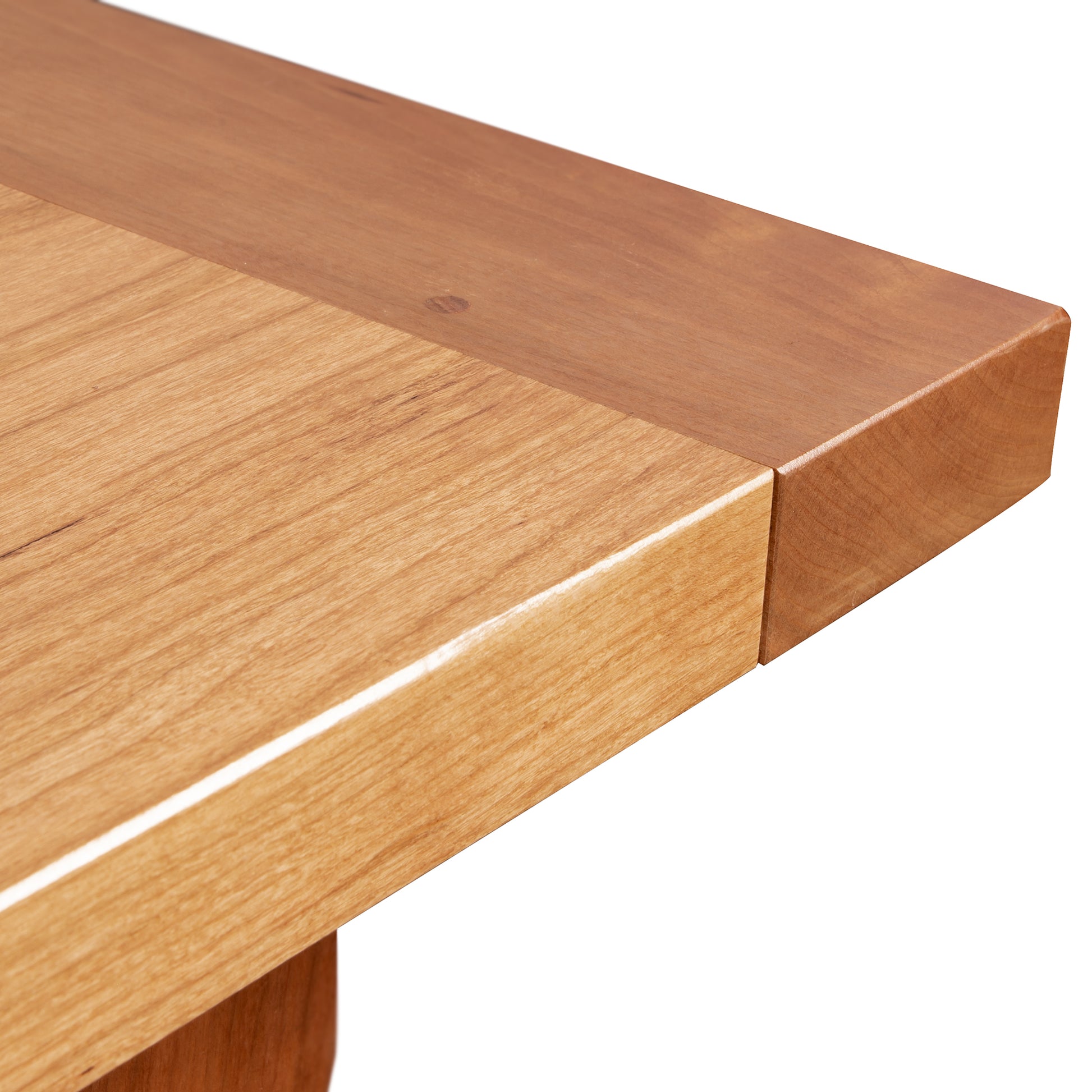 Close-up of a natural cherry Maple Corner Woodworks Vermont Shaker Solid Top Harvest Table corner showing smooth, polished surfaces with visible wood grain, emphasizing the durable construction and quality of the material.
