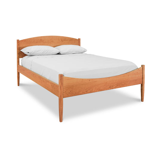 Alt text: Vermont Shaker Moon Bed, a solid wood bed frame with natural finish, featuring simple slatted headboard and no footboard. Made by Maple Corner Woodworks from American-made maple wood, this eco-friendly bed is set up with white fitted sheet and two white pillows against a plain background. Perfect for those seeking shaker furniture and sustainable wooden beds.
