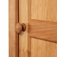 Close-up of a natural cherry hardwood door with a round knob, showcasing craftsmanship similar to the Vermont Shaker bookcase by Maple Corner Woodworks.