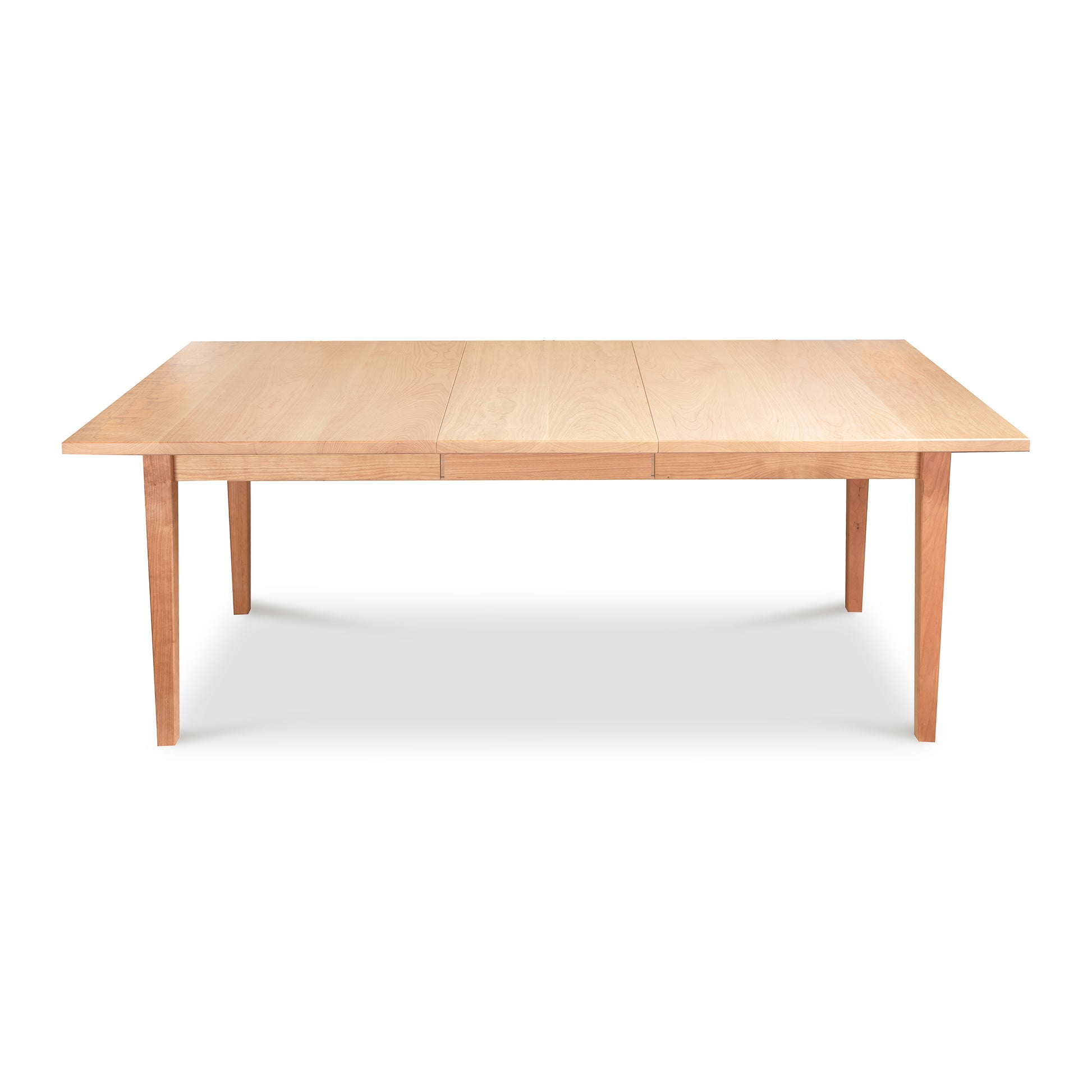 A Vermont Shaker Rectangular Extension Dining Table with a light finish, featuring extendable leaves and simple, straight legs. This sustainably harvested wood table by Maple Corner Woodworks is shown isolated on a white background.