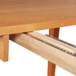 Close-up of a Maple Corner Woodworks Vermont Shaker Rectangular Extension Dining Table showing an extended drawer partially open, with visible dovetail joints and metal drawer slides. The wood has a light natural finish.