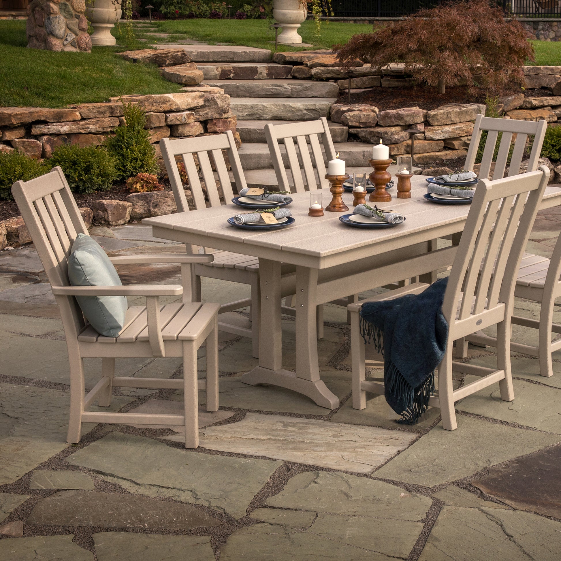 Beige POLYWOOD Vineyard Dining Chairs arranged with place settings and a blue throw, showcasing American-made outdoor furniture quality.