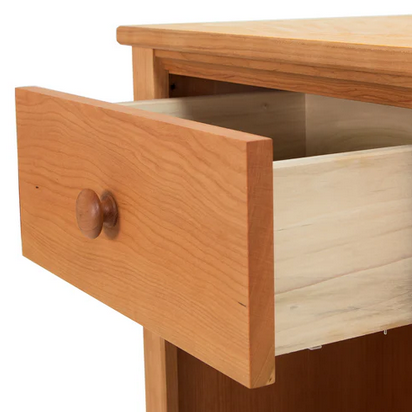 A drawer made from Maple Corner Woodworks, partially open to reveal its light-colored interior, is attached to a piece of wooden furniture with a smooth finish and features the Special Order (Levin) Replacement Vt Shaker Knob as its handle.