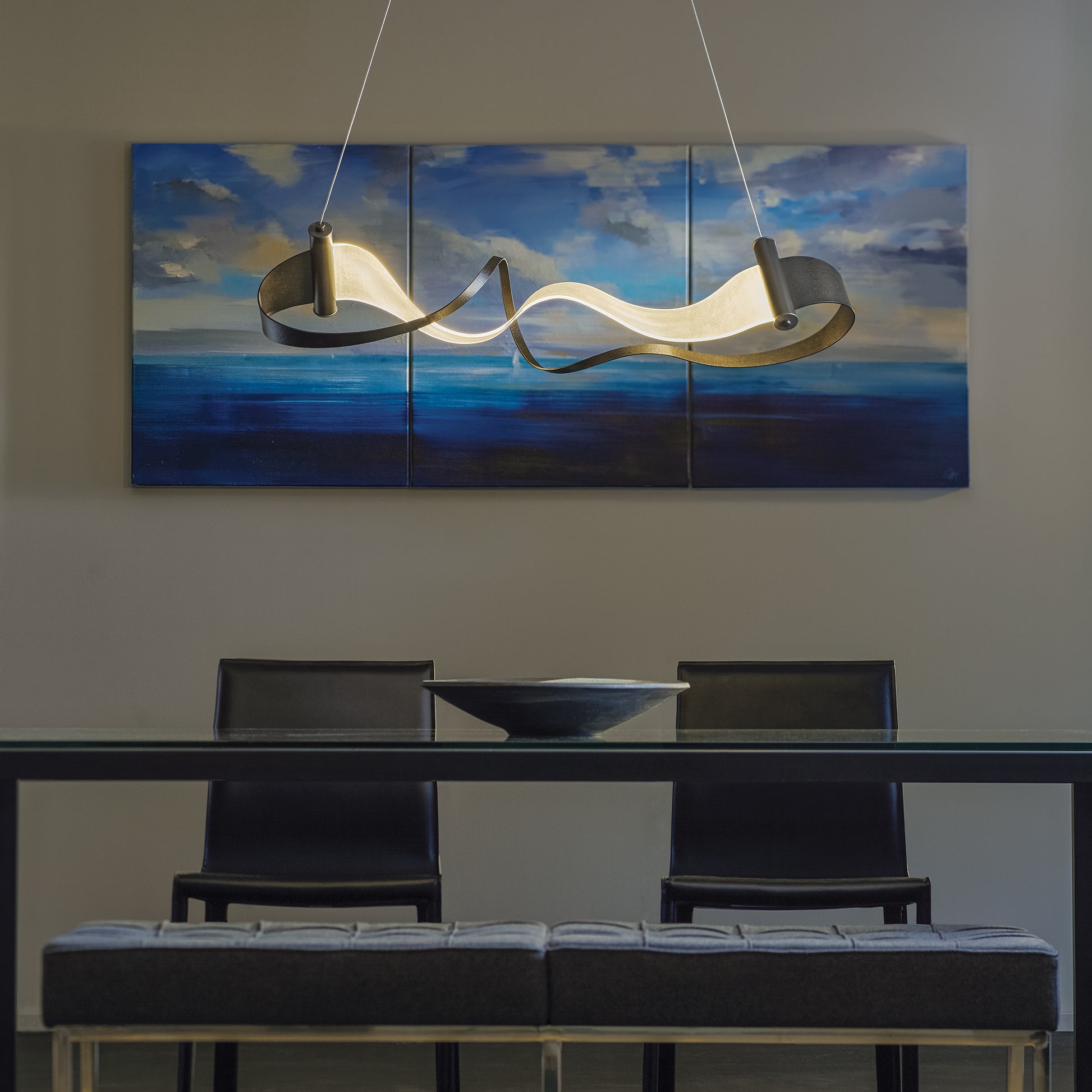 High quality American made glass dining table with sleek black chairs, crafted for modern style and durability; abstract art in the background.