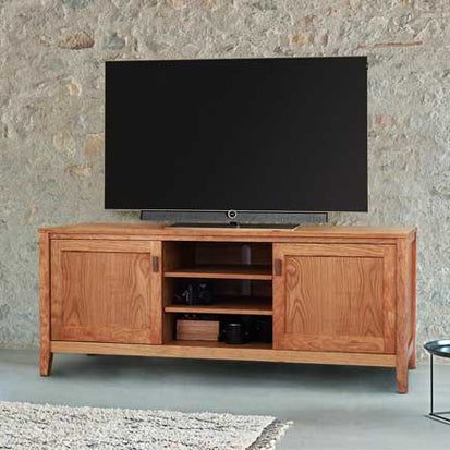 A wooden tv stand in front of a stone wall.