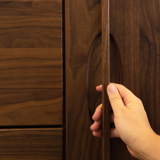 A person opening a wooden door with a hand.