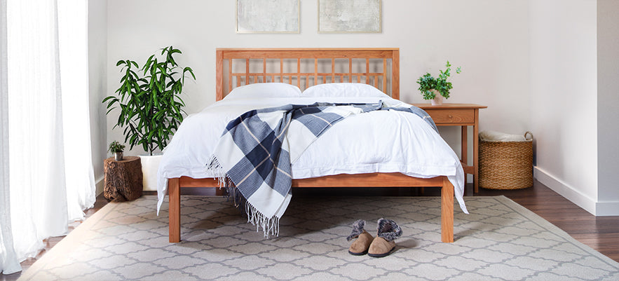 Elegantly crafted bed with a plaid blanket, showcasing American made furniture excellence.